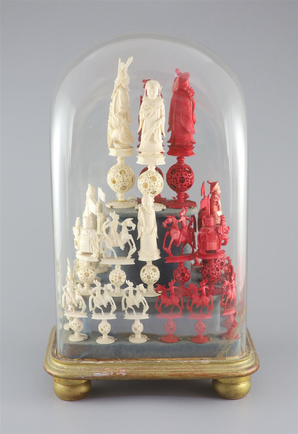 A set of 19th century Cantonese carved and red stained ivory chess pieces under dome, white king 20cm high